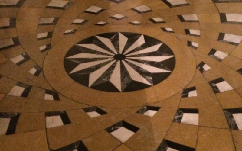 Pavimento in marmo con decoro centrale a rosone e fasce che si dipartono dal centro